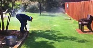 Sprinkler repair specialist checking on a sprinkler head